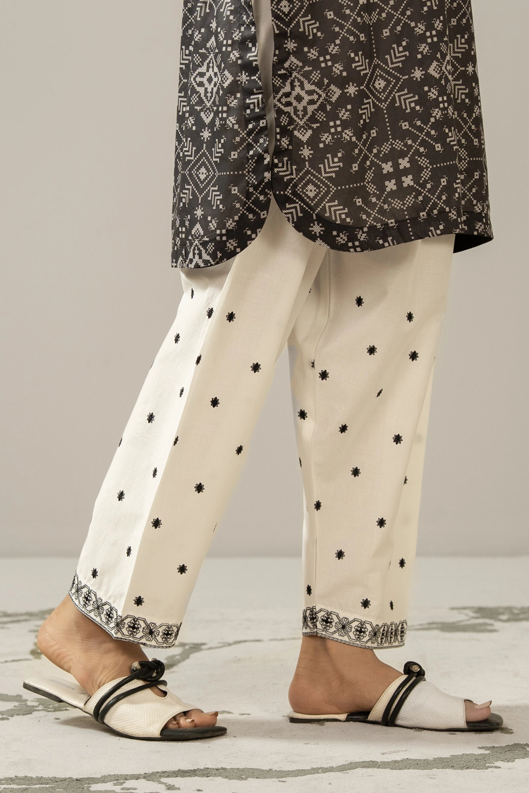 Stitched white cambric shalwar featuring delicate tone-on-tone embroidery on the borders from the Monochrome Collection