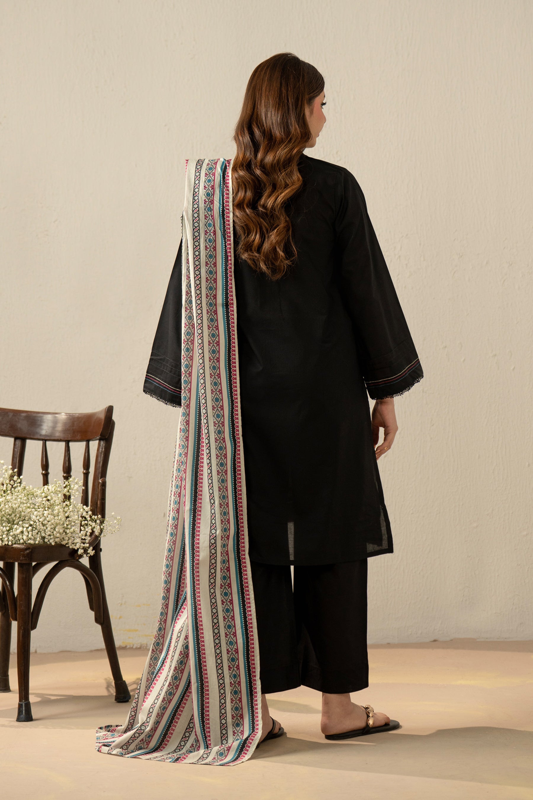 High-fashion stitched 3-piece black cambric suit with unique stylized cuts, matching dupatta, and trousers