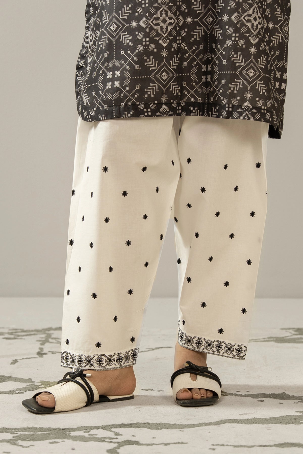 Stitched white cambric shalwar featuring delicate tone-on-tone embroidery on the borders from the Monochrome Collection
