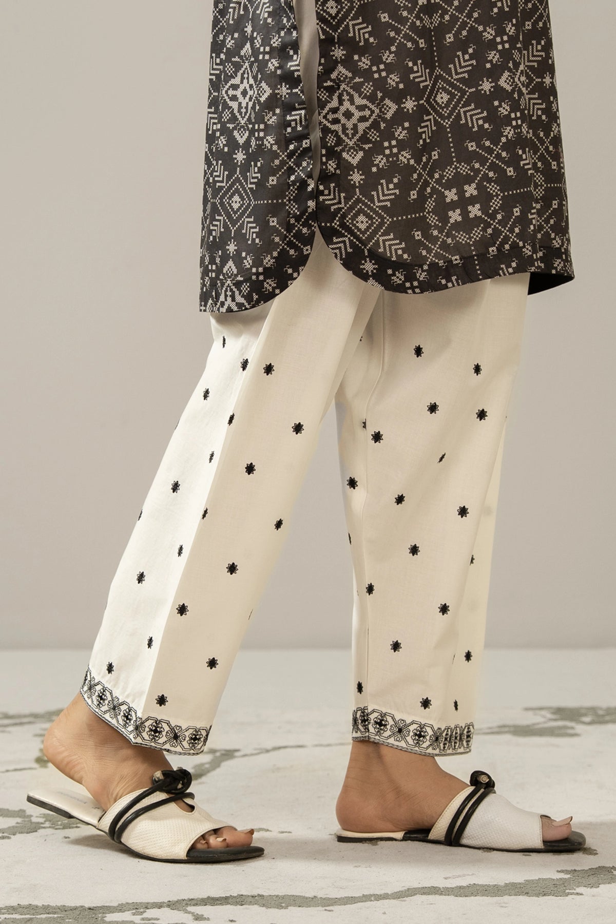 Stitched white cambric shalwar featuring delicate tone-on-tone embroidery on the borders from the Monochrome Collection