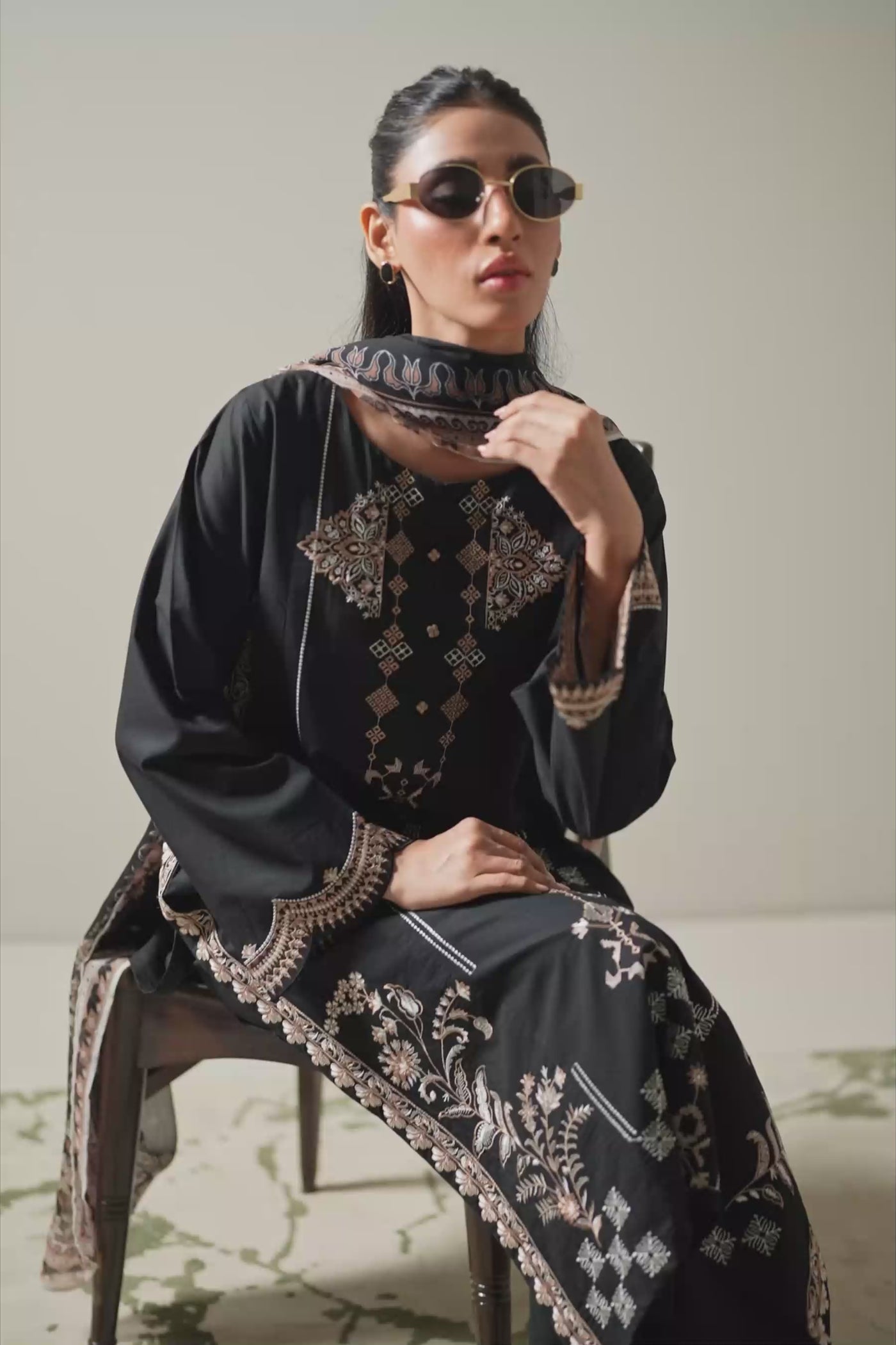 Premium stitched 3-piece black cambric suit displaying a mix of fine prints and embroidery, complete with a dupatta and matching trouser